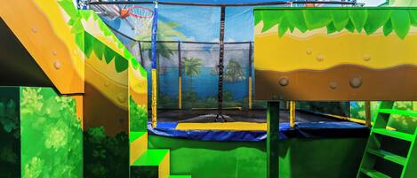 A trampoline area with netted safety, a basketball hoop, and a ladder.