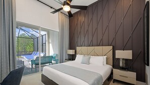 A modern hotel room with a large bed, a nightstand, a chair, and a view of an outdoor pool area. - The Village, Homes by Villatel (Davenport)