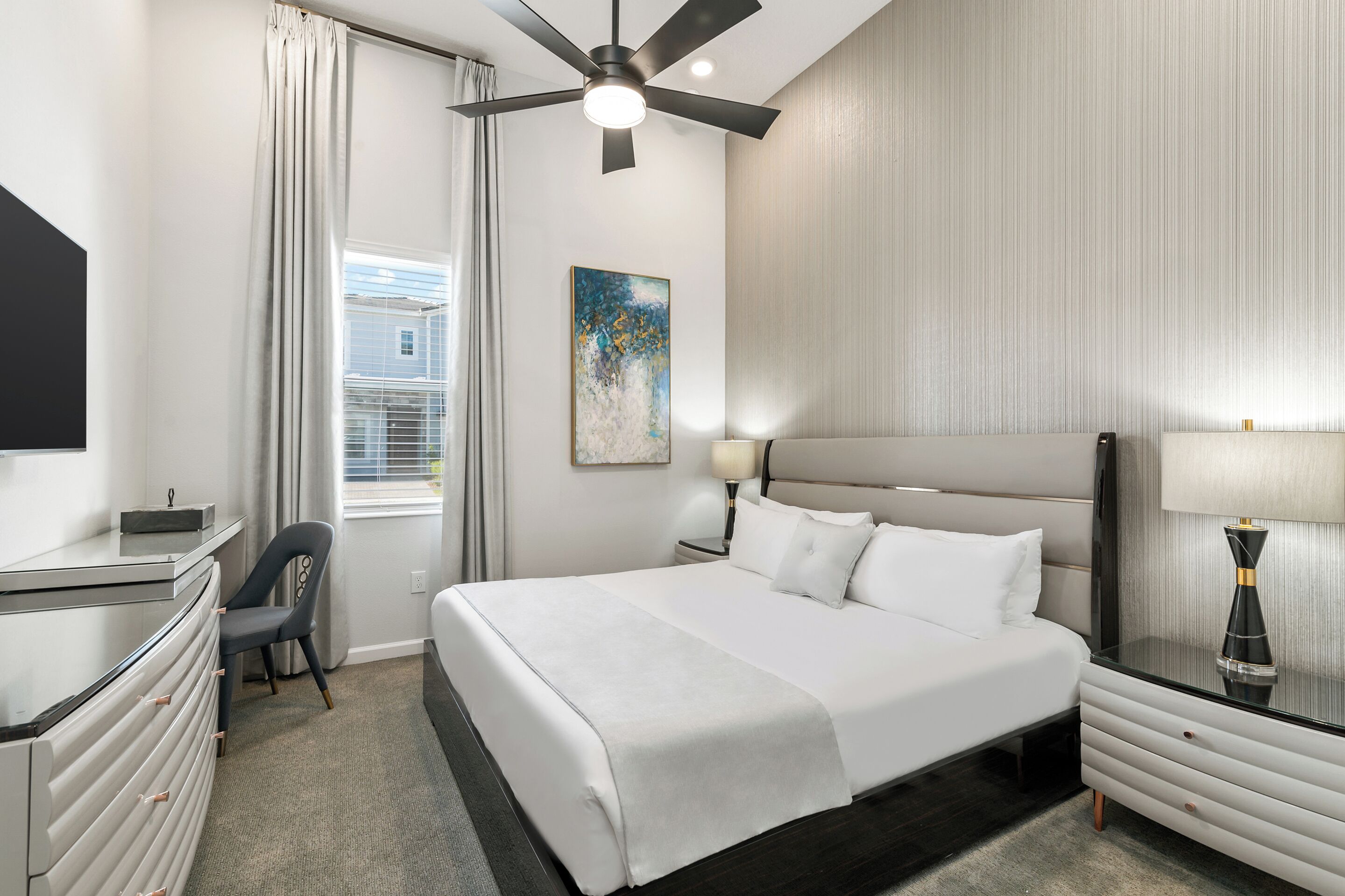 Une chambre d’hôtel équipée d’un lit, d’un bureau, d’une chaise et d’un ventilateur de plafond.