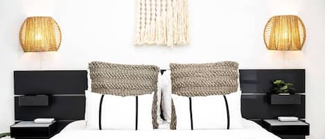 A modern bedroom with a large bed, two nightstands, a wall-mounted macrame piece, and two textured wall lamps.