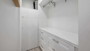 Un placard blanc avec une porte, un comptoir blanc et une étagère en métal.