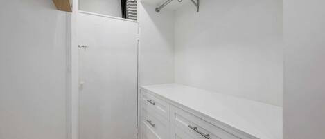 A white closet with a door, a white countertop, and a metal rack.