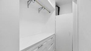 Een witte kast met een metalen rek en een houten vloer.