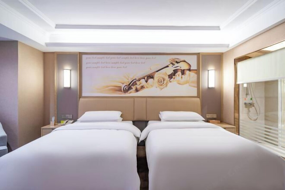 A hotel room with two beds, a large wall-mounted artwork, bedside lamps, and a window with blinds.