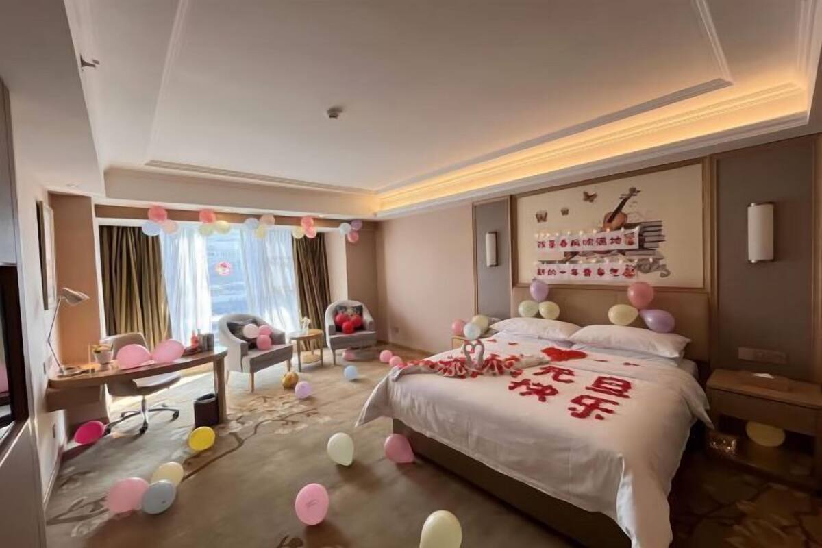 A hotel room with a bed, a desk, a chair, and a window with curtains.