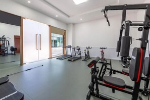 A gym with exercise equipment, a bench, and a treadmill.