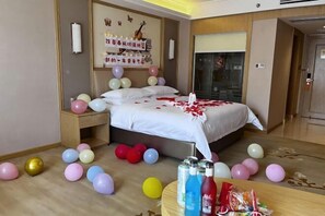A hotel room with a bed, bedside tables, balloons, and a table with snacks and drinks. - Vienna International Hotel (Guiyang Yunyan District Future Ark Branch) (Guiyang)