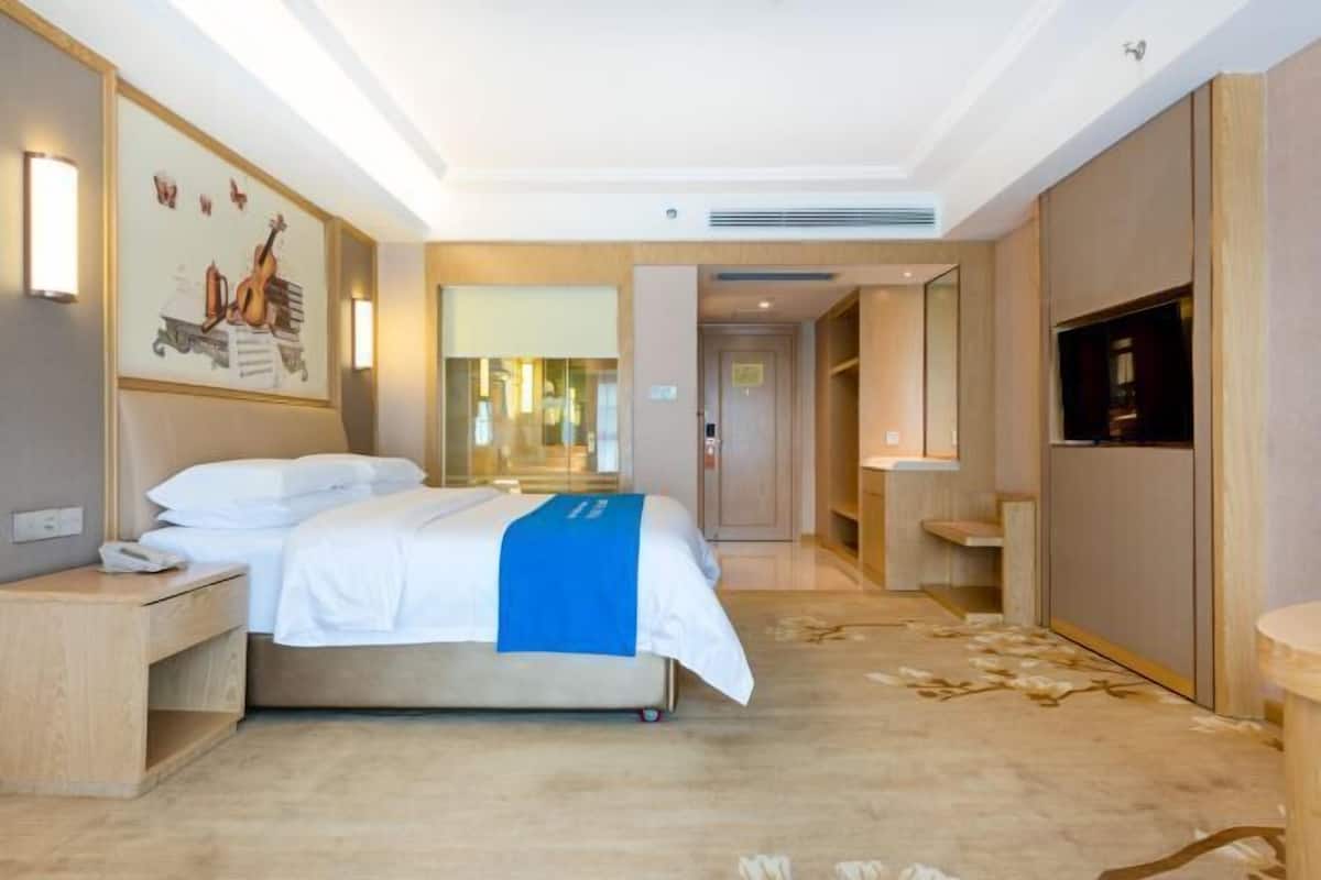 A modern hotel room with a bed, bedside table, and a large mirror.