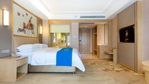 Una habitación de hotel moderna con cama, mesita de noche y un espejo grande.