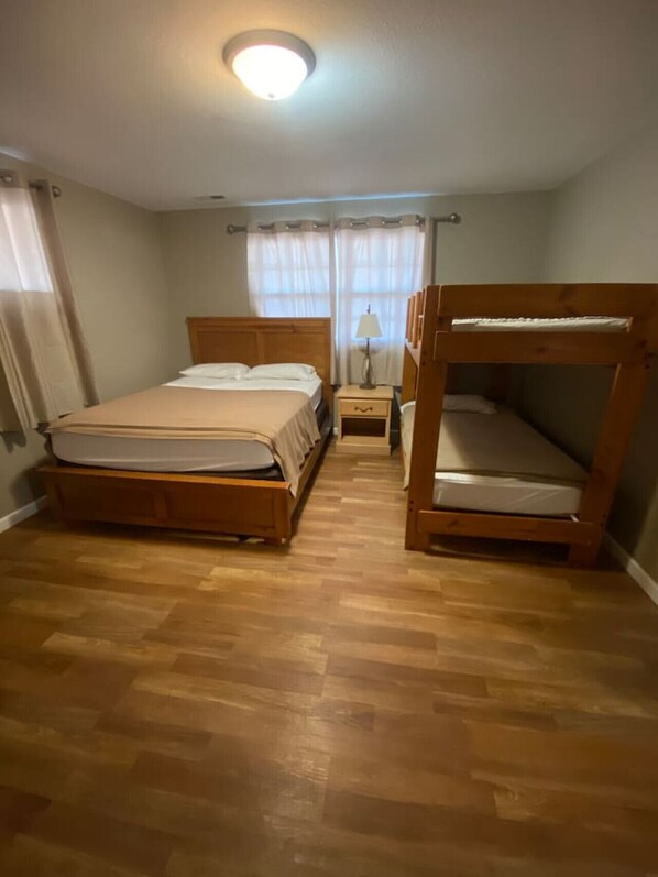 Una habitación con una cama de madera, una mesita de noche y una cama litera.