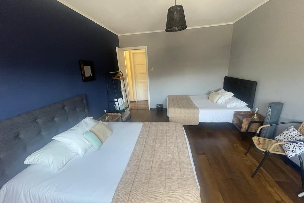 Une chambre d’hôtel avec deux lits, une chaise, une table de chevet et un luminaire suspendu.