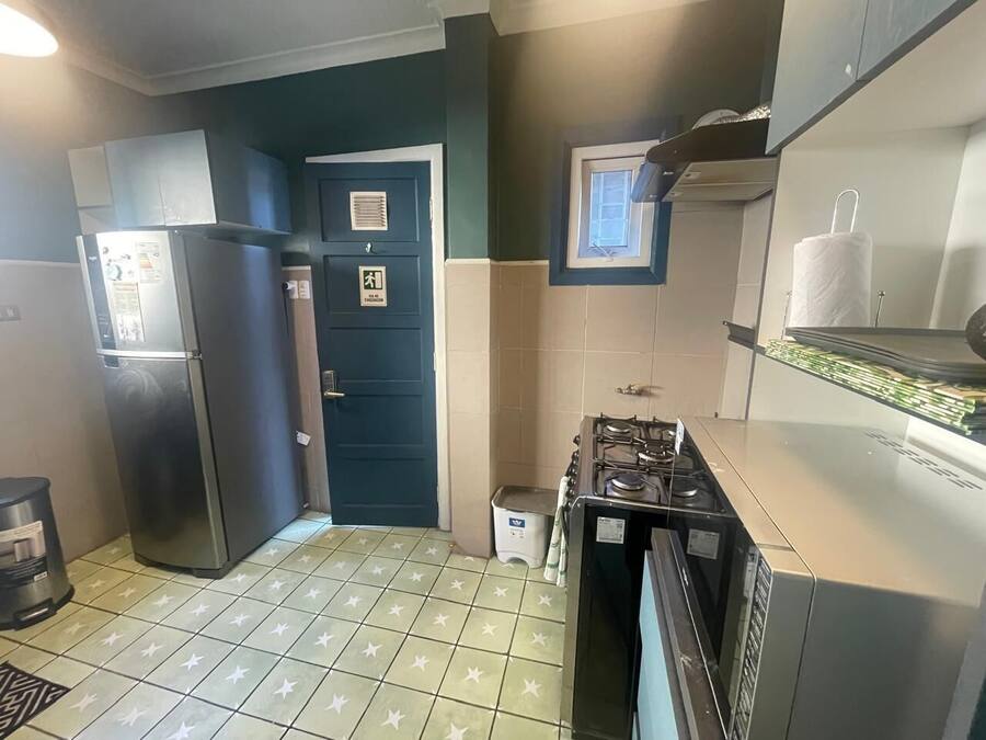 A compact kitchen with a refrigerator, stove, and a small window.