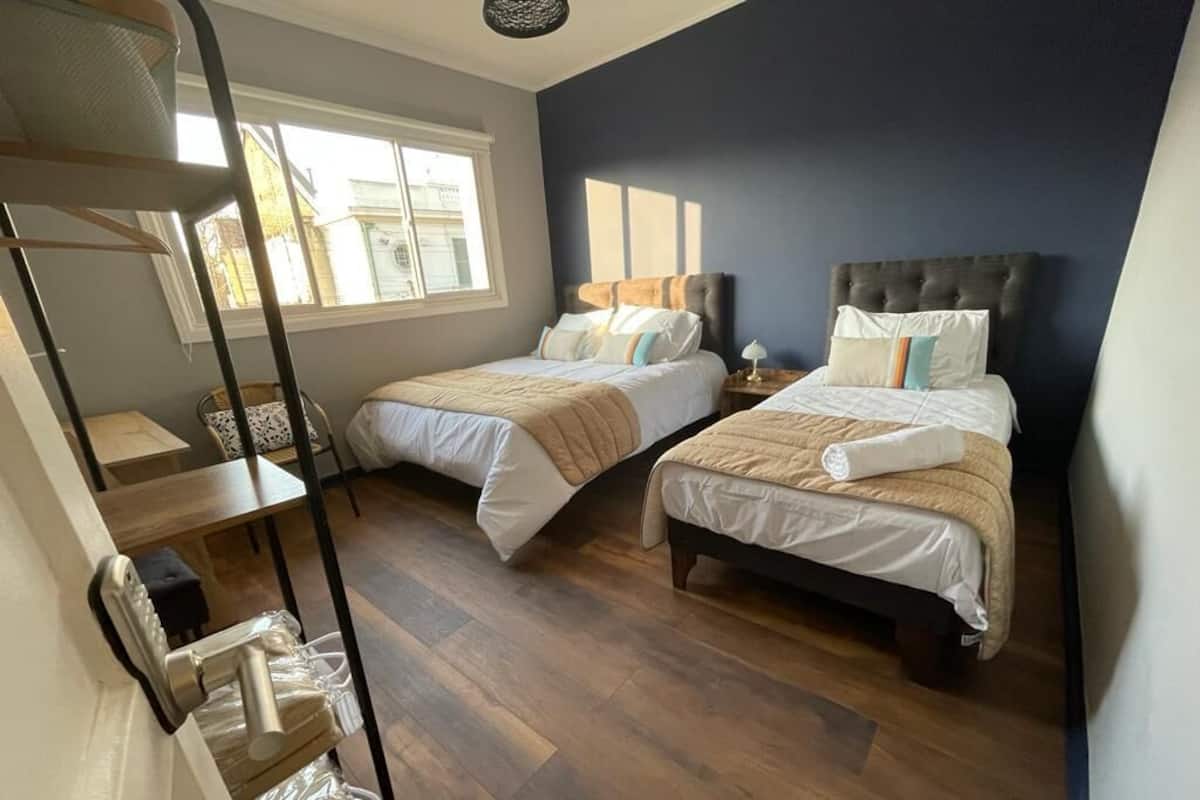 Une chambre avec deux lits, une fenêtre et un plancher en bois.