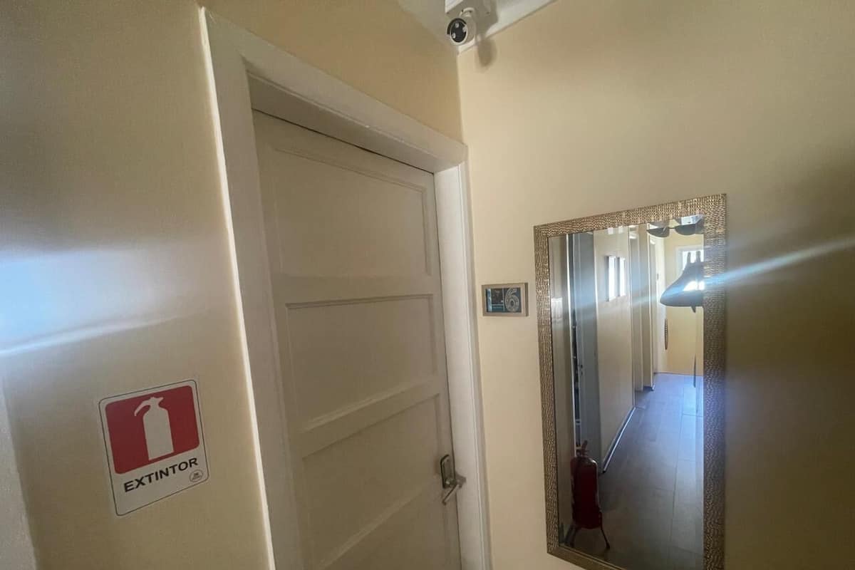 Un couloir avec une porte sur laquelle est inscrit « EXTINCTEUR » et un miroir accroché au mur.
