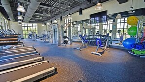 Un gimnasio con cintas de correr, máquinas de pesas y pelotas de ejercicio.