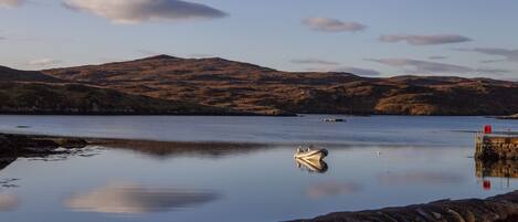 A calm lake with a small boat anchored near a stone wall.