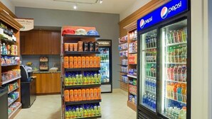A grocery store aisle with shelves stocked with beverages, a Pepsi refrigerator, and a section labeled "Proudly Brewed Coffee." - Super Bowl Week! (Phoenix)