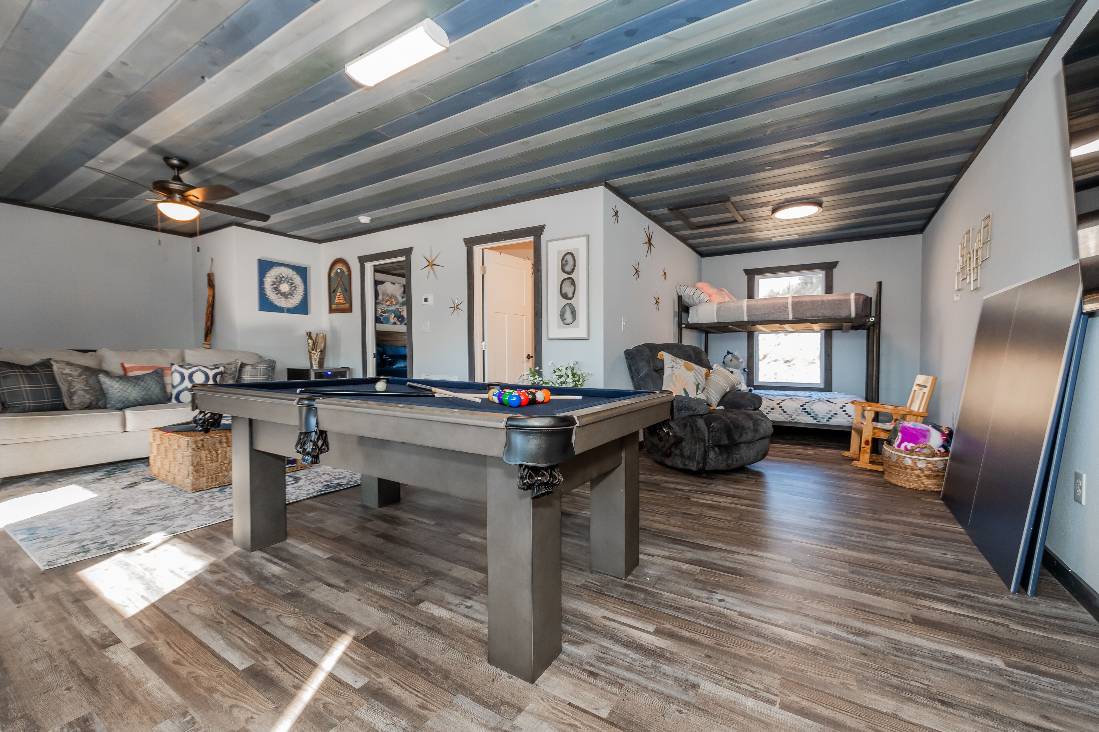 A spacious living area with a pool table, a sofa, and a ceiling fan.