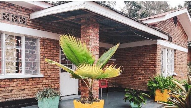 Een huis met een bakstenen gevel, een overdekte veranda en potplanten.