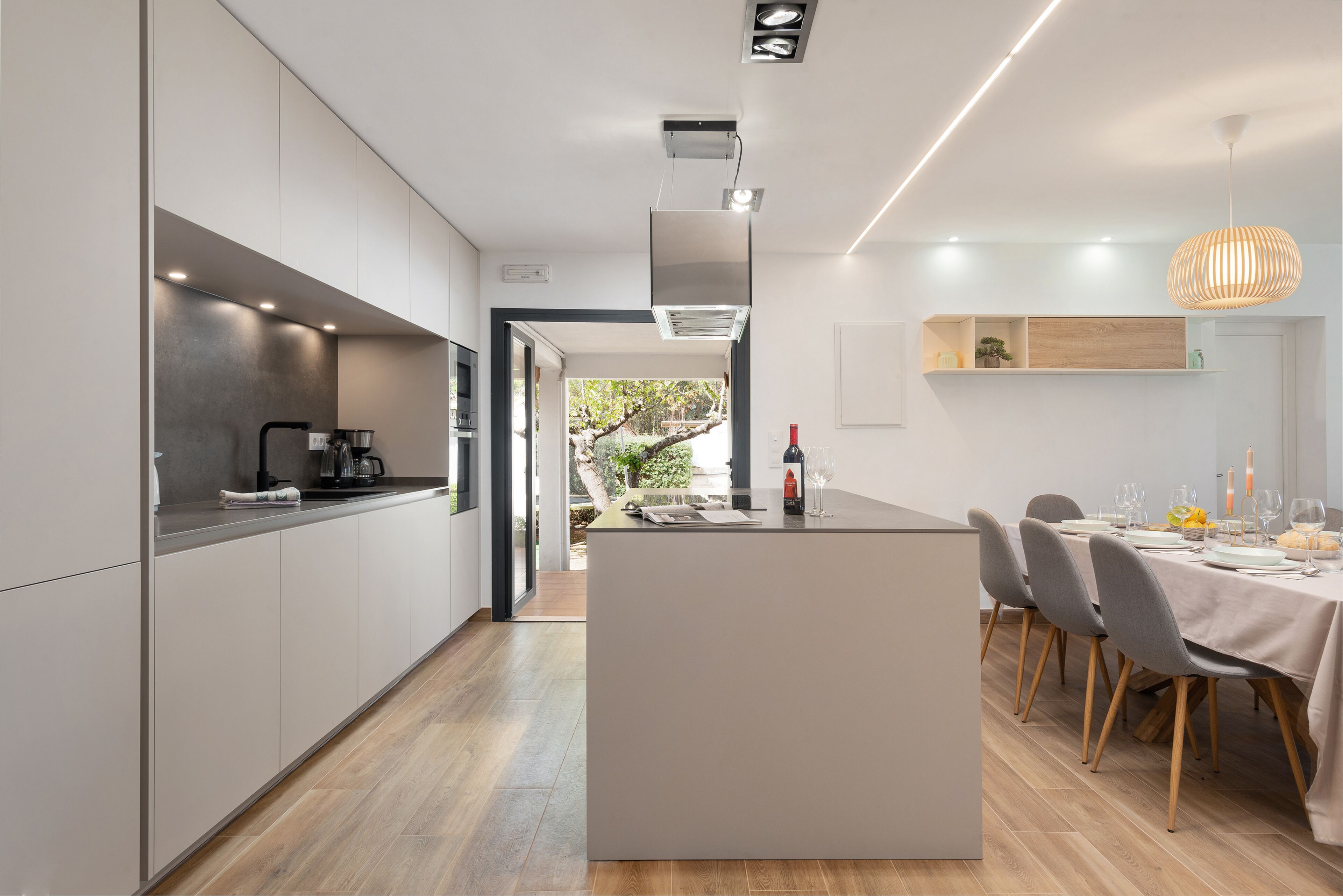 A modern kitchen with a central island, built-in appliances, and a dining area with a table set for four.