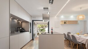 A modern kitchen with a central island, built-in appliances, and a dining area with a table set for four. - Villa Volentina, private pool, pool table, free WiFi (Puerto de Pollensa)