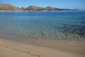 A beach with clear shallow waters, a sandy shore, and distant mountains. - Villa Volentina, private pool, pool table, free Wi-Fi (Puerto de Pollensa)