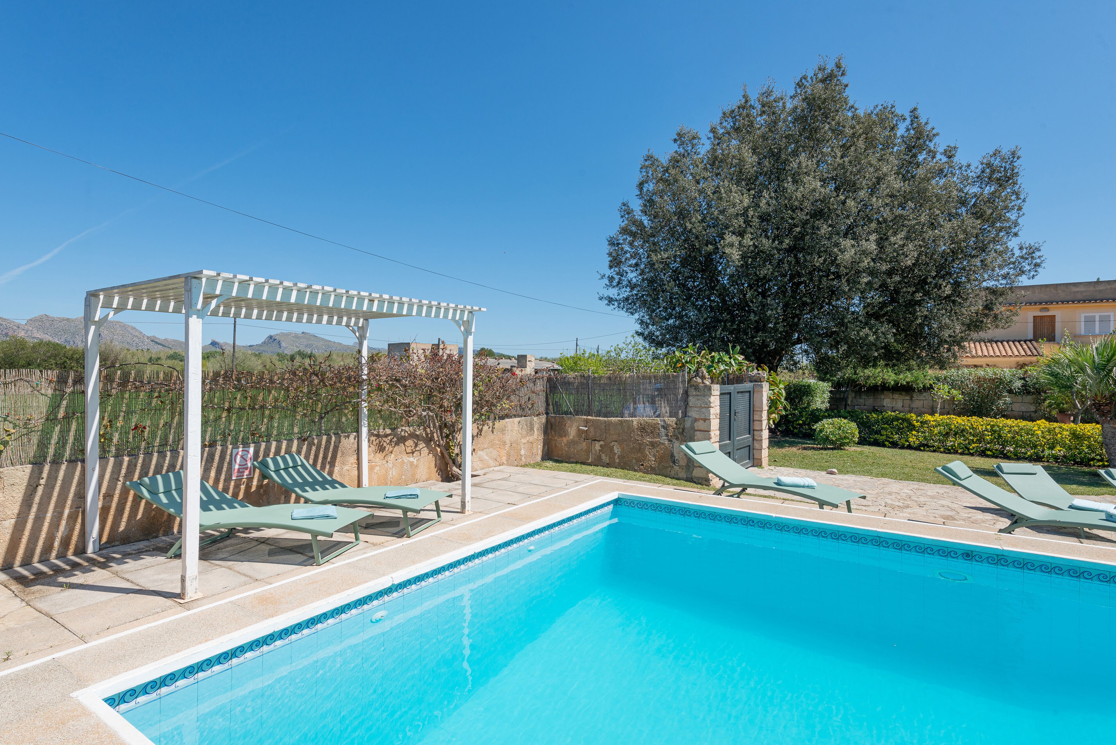 A swimming pool with lounge chairs and a pergola.