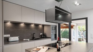 A modern kitchen with a built-in oven, a coffee maker, and a toaster on the counter. - Villa Volentina, private pool, pool table, free WiFi (Puerto de Pollensa)