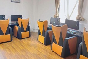 A room with four orange and black chairs, a desk with a computer, and a window with curtains. - Bierga Grand Hotel (Fuqing)