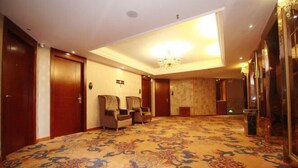 Un vestíbulo de hotel con suelo alfombrado, puertas de madera y una lámpara de araña.