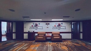 Un salón de conferencias con dos sofás de cuero marrón, una pizarra con texto y un suelo de madera con motivos.