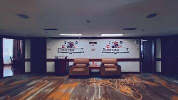 Un salón de conferencias con dos sofás de cuero marrón, una pizarra con texto y un suelo de madera con motivos.