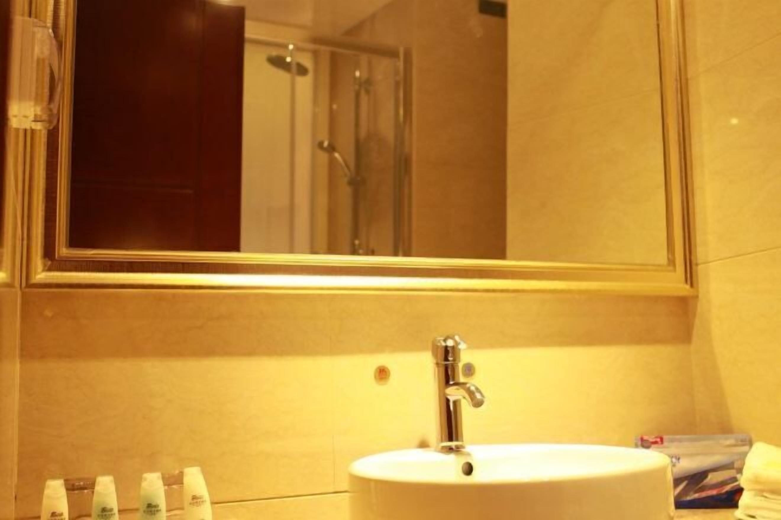 Un baño con un lavabo blanco, un espejo y artículos de tocador en la encimera.