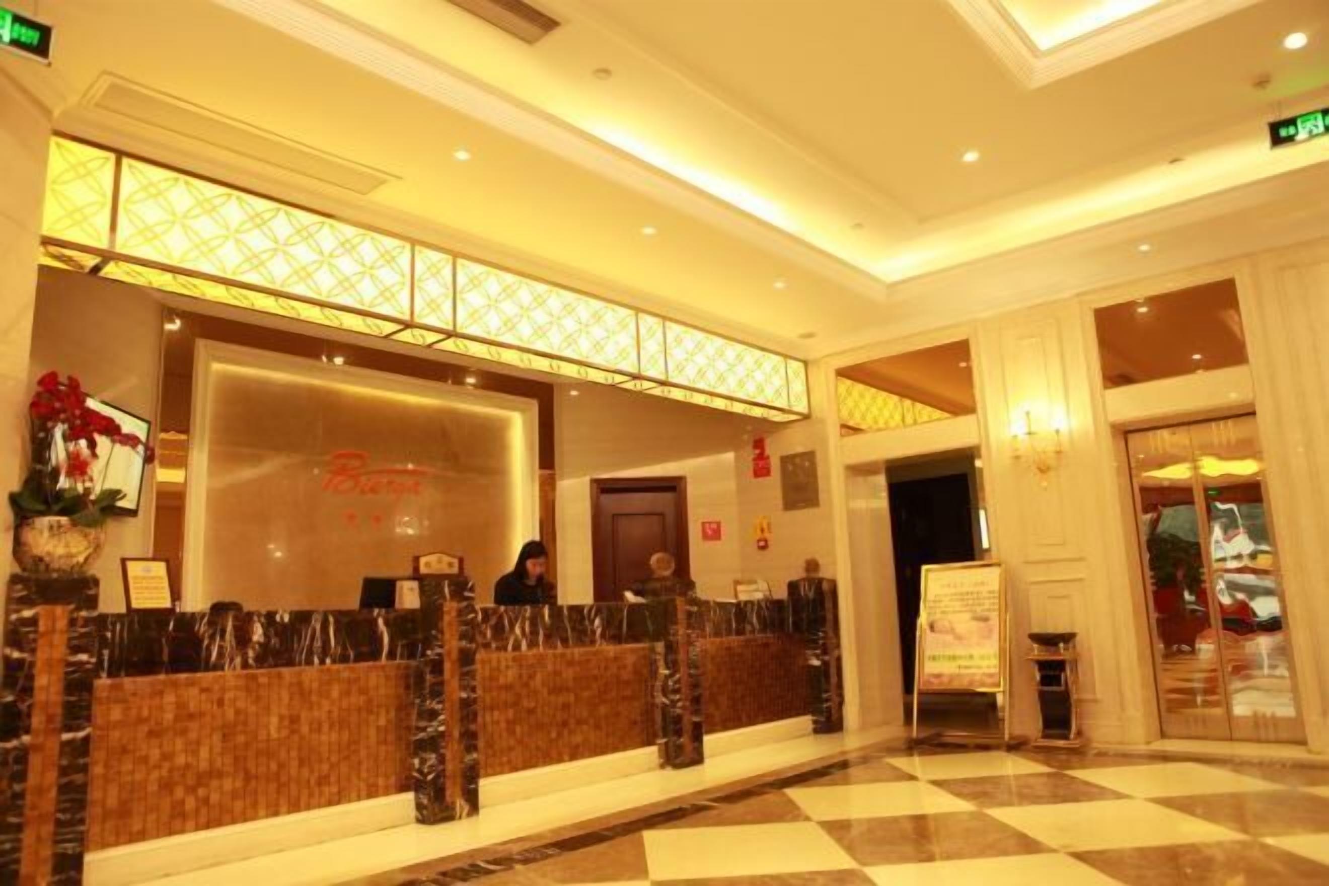 Un'area della reception di un hotel con una scrivania per il check-in, un banco informazioni e una sala d'attesa con sedie.