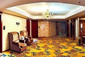 A hotel lobby with a patterned carpet, a chandelier, and two armchairs. - Bierga Grand Hotel (Fuqing)