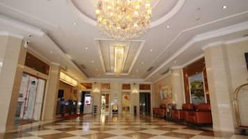 Vestíbulo de hotel con piso a cuadros, un candelabro y una zona de recepción.