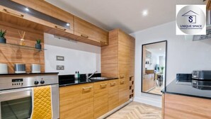 A modern kitchen with wooden cabinets, stainless steel appliances, and a herringbone floor pattern.