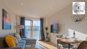 A modern living room with a sofa, a dining table, and a TV.
