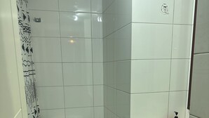 A small bathroom with white tiles, a toilet, a sink, and a shower curtain. - Central Suites (Santiago)