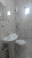 Casa de banho com lavatório branco, sanita e zona de duche.