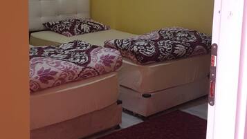 A room with two beds, a red carpet, and a white ceiling with a light fixture.
