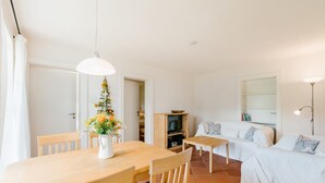 A cozy living room with a wooden dining table, a sofa, and a TV stand. - Allgäu a. Forggensee - near Neuschwanstein, apartment f. Couples and family, 2 bedrooms, WLAN (Roßhaupten)