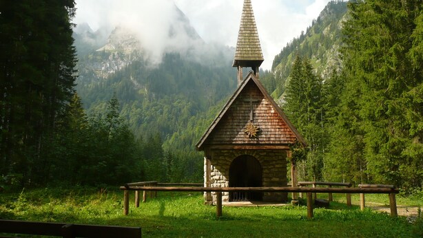 A small wooden chapel with a pointed steeple, surrounded by lush greenery and mountains. - Allgäu a. Forggensee - near Neuschwanstein, apartment f. Couples and family, 2 bedrooms, WLAN (Roßhaupten)