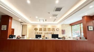 A hotel reception area with a reception desk, a large sign with hotel name, and a window to the right.