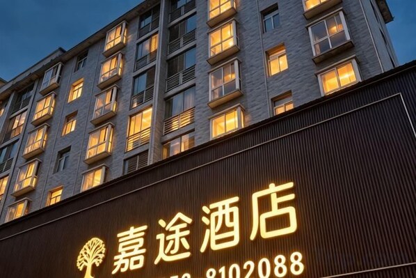 A hotel with a signboard displaying the name and contact number.