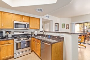 A modern kitchen with wooden cabinets, stainless steel appliances, and a granite countertop.