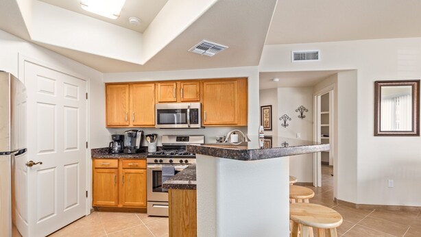 Una cocina moderna con armarios de madera, electrodomésticos de acero inoxidable y una isla central con taburetes.