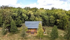 A cabin with a sloped roof surrounded by dense forest.