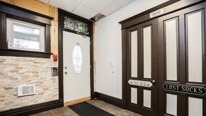 Un couloir avec un mur en pierre, une porte sur laquelle est affiché un panneau indiquant « Chaussettes perdues », et un autre panneau indiquant « Entrez, sortez, lavez-vous ».