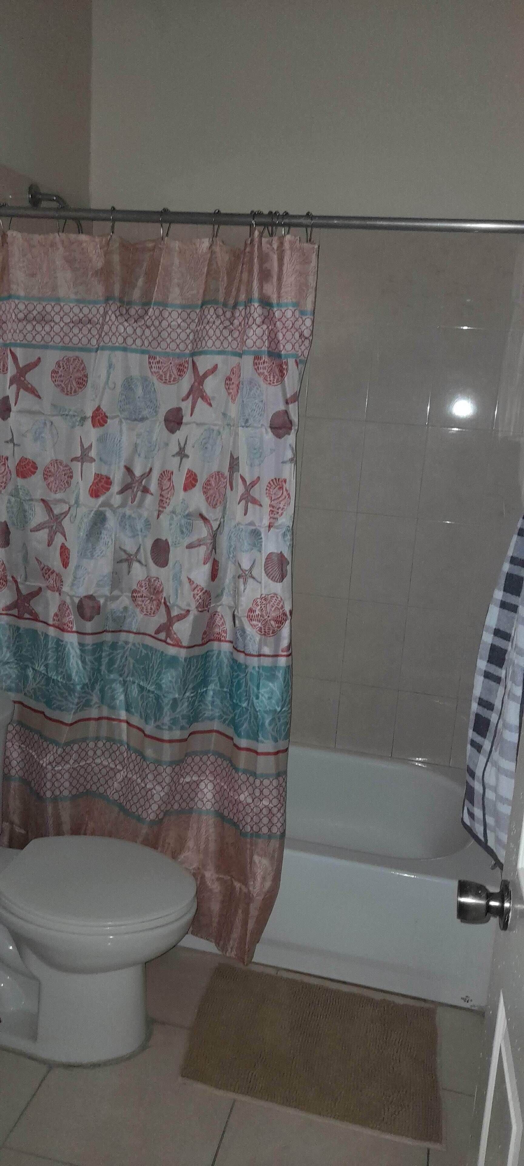 A bathroom with a toilet, bathtub, and shower curtain.